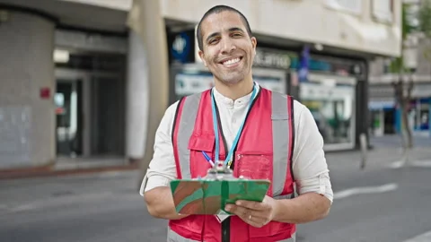 Young hispanic man volunteer smiling writing on clipboard at street Stock Footage 245022524