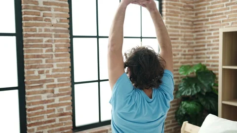 Young hispanic man waking up stretching arms at bedroom Video stock 231507797