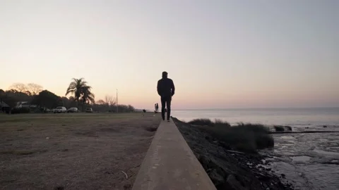 Young hispanic man walks next to the river at sunset in Argentina Stock Footage 201202432