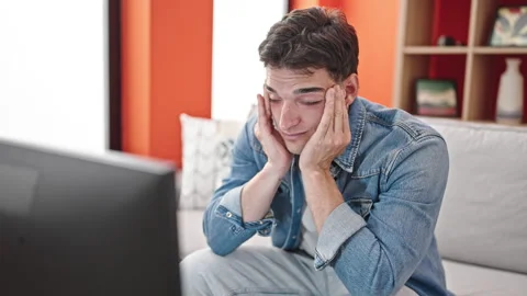 Young hispanic man watching tv wearing glasses for vision problem at home Stock Footage 243481499
