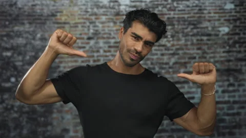 Young hispanic man wearing a black t shirt pointing thumbs to himself again.. Video stock 314245300