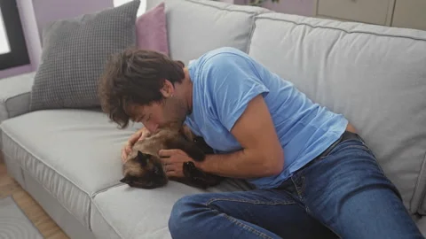 A young hispanic man wearing a blue shirt lovingly kisses his pet cat while.. Stock Footage 283549608