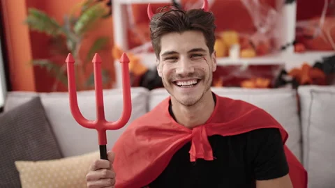 Young hispanic man wearing devil costume holding trident at home Stock Footage 232257700