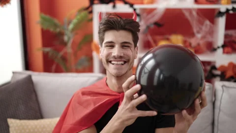Young hispanic man wearing devil costume holding balloon at home Stock Footage 232875972