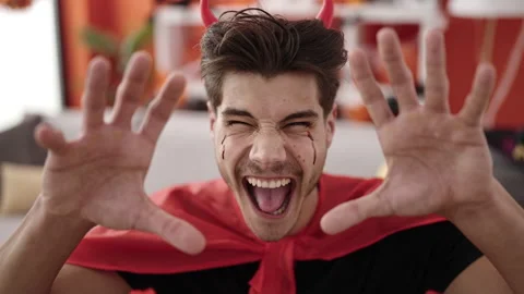 Young hispanic man wearing devil costume doing scare gesture at home Stock Footage 233416791