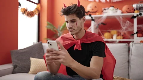 Young hispanic man wearing devil costume using smartphone at home Stock Footage 234166421