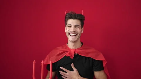 Young hispanic man wearing devil costume holding trident over isolated red .. 動画素材 236566900