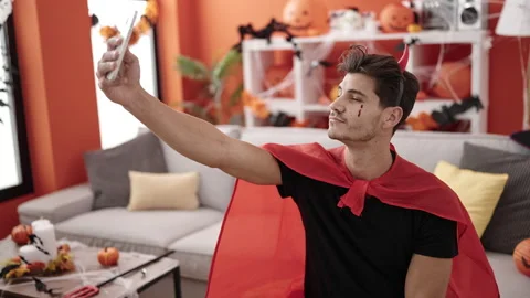 Young hispanic man wearing devil costume make selfie by smartphone at home Stock Footage 236801288