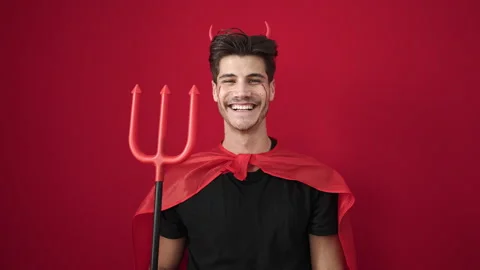 Young hispanic man wearing devil costume holding trident over isolated red .. 動画素材 237845073