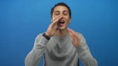 Young hispanic man wearing gray sweater against a solid blue background app.. Stock Footage 315176091