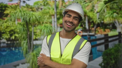 Young hispanic man wearing hardhat and neon vest with arms crossed beside p.. Stock Footage 313865485