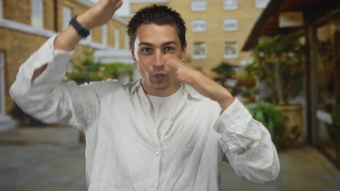 Young hispanic man wearing a loose white shirt frames his face with hands o.. Stock Footage 314298860