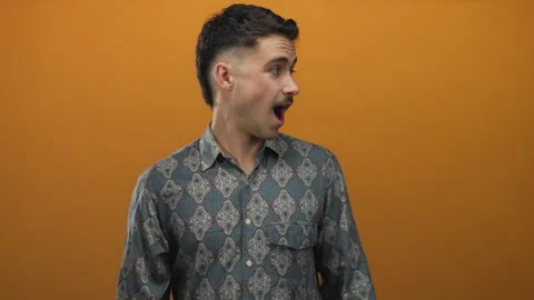 Young hispanic man wearing a patterned shirt looks surprised against a vibr.. Stock Footage 313025125