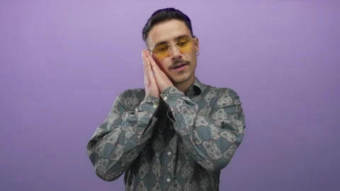 Young hispanic man wearing patterned shirt makes a sleeping gesture on an i.. Stock Footage 313857867