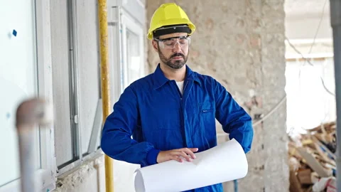 Young hispanic man worker wearing hardhat holding blueprints at constructio.. 스톡 동영상 245079974