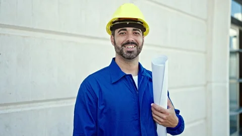 Young hispanic man worker wearing hardhat holding blueprints at constructio.. 스톡 동영상 247911176
