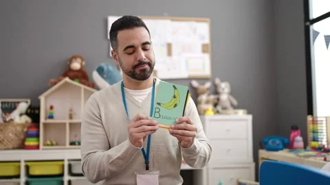 Young hispanic man working as teacher teaching words at kindergarten Video stock 232876327