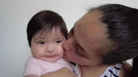Young hispanic mom hugging and kissing her baby girl on the cheek Stock-Footage 243175058