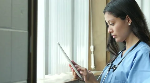 Young hispanic nurse using an ipad in a medical setting Stock Footage