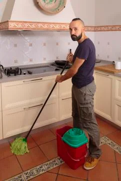 Young hispanic self-sufficient man mopping the floor Stock Photos