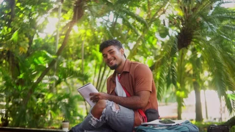 Young hispanic student reading a book in a sunny park Stock Footage 318012583