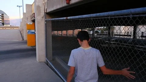 A young Hispanic teen walking in a city parking garage - bored Stock Footage