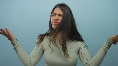 Young hispanic woman expressing confusion against a solid blue background w.. Stock Footage 313080853