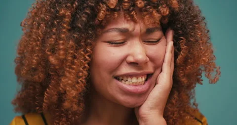 Young Hispanic woman feeling teeth pain on blue background Stock Footage 317465337