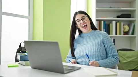 Young hispanic woman student using pen as a drummer at library university Stock Footage 242364044