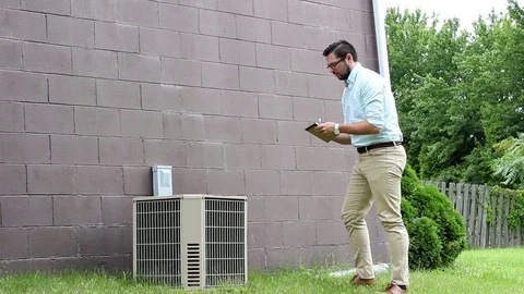 Young Home inspector or Contractor takes notes of an old AC unit Stock Footage 78045493