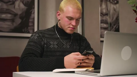 Young homosexual man using phone, sitting at home office. Man holds smartphone Stock Footage 146909025