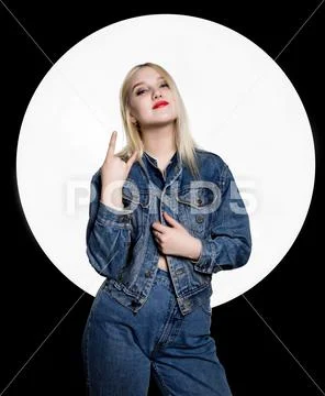 Young hooligan in jeans and a denim jacket shows different signs with her Stock Photos