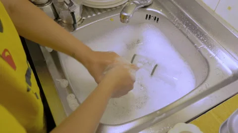 Young housewife washing thoroughly glasses in the sink Stock Footage