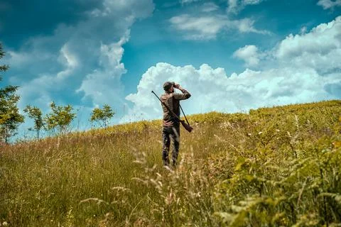 Young hunter on a hill checking his surrounding for prey Stock Photos