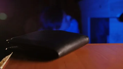 Young inattentive guy trying to find lost black wallet in the office at night. 動画素材 106470849