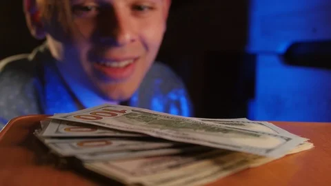 Young inattentive guy trying to find lost money in the office at night. Happy Stockbeeldmateriaal 106470850