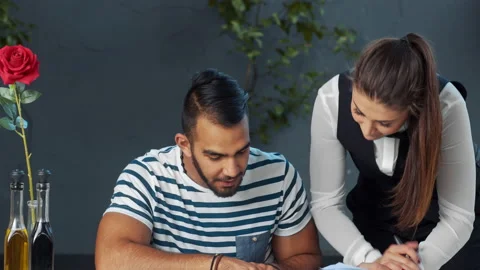Young independent middle eastern man giving meal order to waiter in cafe. Video stock 199634955