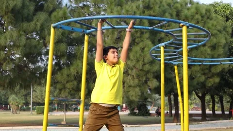 Young indian boy actively hanging and swinging on monkey bars at a outdoor .. Vídeo Stock 329091820