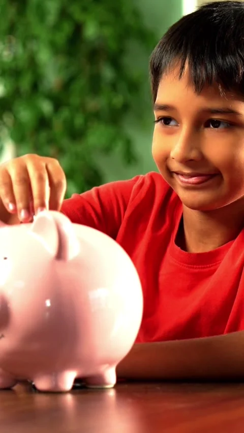 Young Indian boy placing coins in piggy bank at home Video stock 343214563