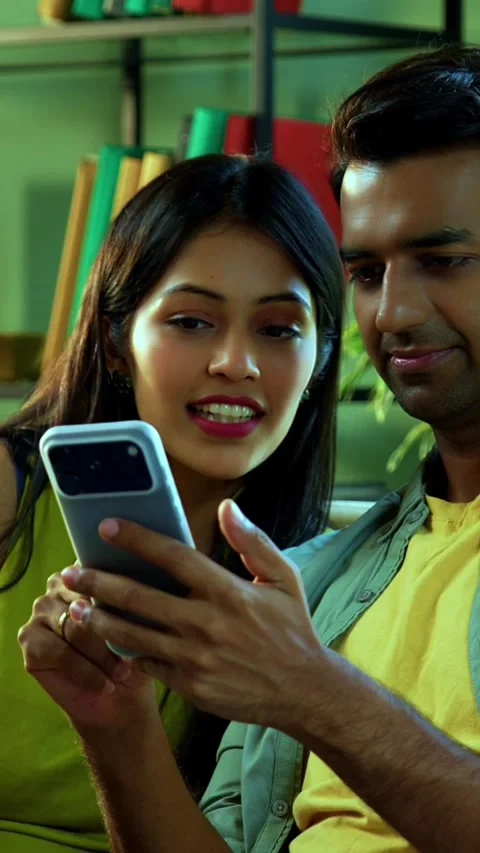 Young Indian couple browsing mobile phone together while relaxing on sofa Stock Footage 342689356