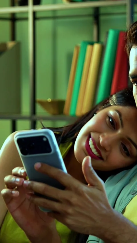 Young Indian couple browsing mobile phone together while relaxing on sofa Stock Footage 342689360