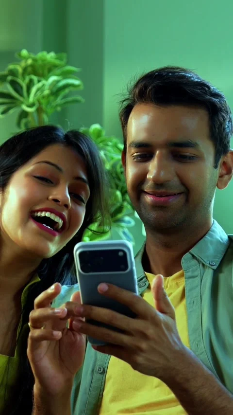 Young Indian couple browsing mobile phone together while relaxing on sofa Stock Footage 342689363