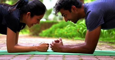 Young Indian couple doing plank exercise facing each other outdoors Stock Footage 342845252