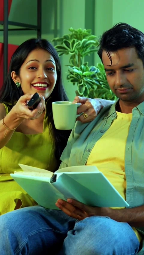 Young Indian couple sitting on sofa watching television together at home Stock Footage 342689319