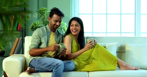 Young Indian couple sitting on sofa having a positive conversation over coffee Stock Footage 342692086