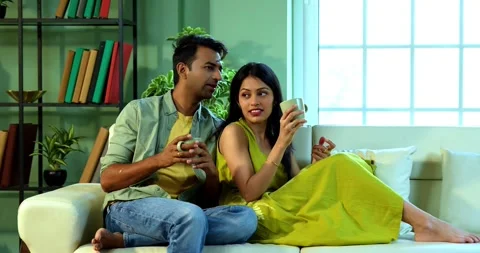 Young Indian couple sitting on sofa having a positive conversation over coffee Vídeo Stock 342692139