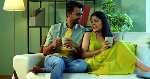 Young Indian couple sitting on sofa having a positive conversation over coffee Vídeo Stock 342692158