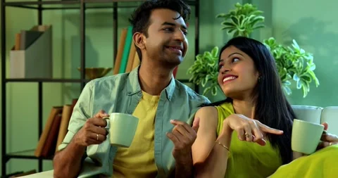 Young Indian couple sitting on sofa having a positive conversation over coffee Vídeo Stock 342692182