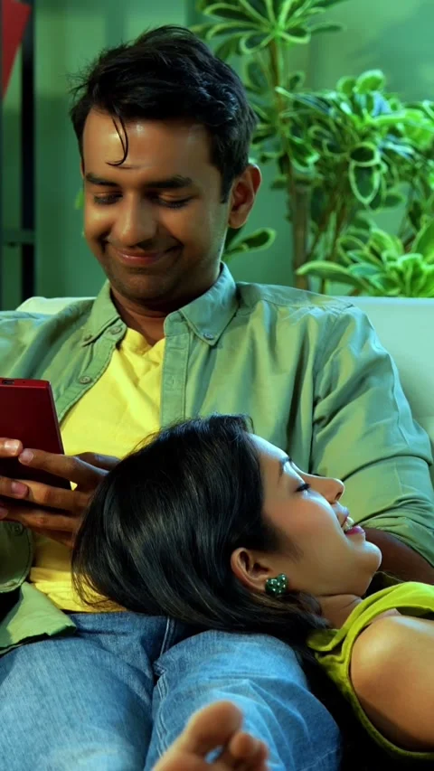 Young Indian couple using mobile phones while sitting on sofa at home Stock-Footage 342689272