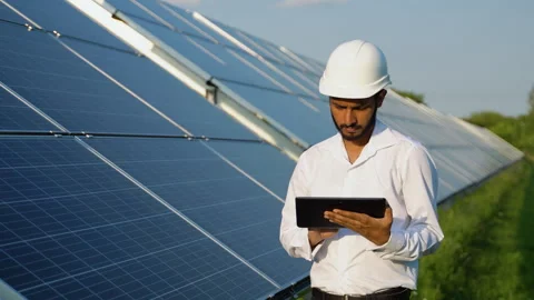 Young indian engineer working on tablet standing near solar panels with clear 스톡 동영상 246817425